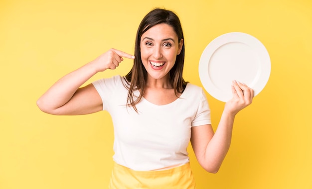 Adulto joven mujer bonita chef casero con plato vacío