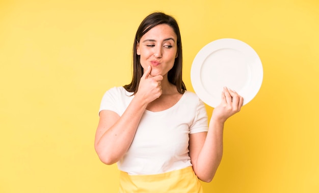 Adulto joven mujer bonita chef casero con plato vacío