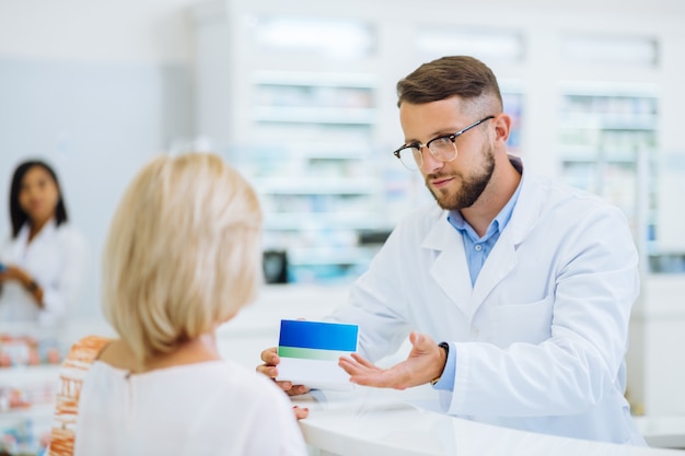 Adulto joven. Persona del sexo masculino guapo con uniforme estéril mientras trabajaba en la farmacia