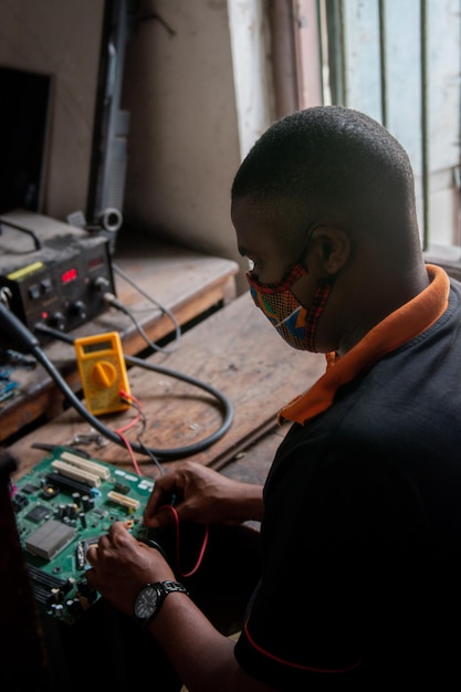 Un adulto joven reparando una placa base de una computadora en un taller