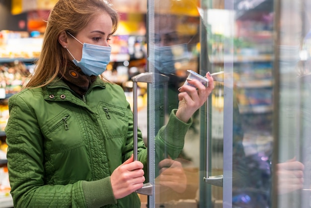 Foto adulto joven usando una máscara de protección y recogiendo productos