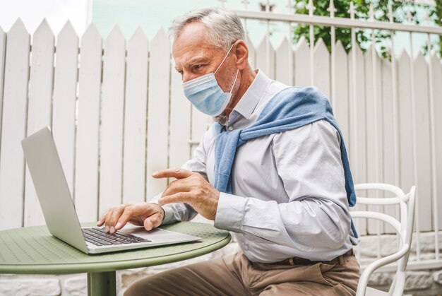 Adulto maduro usando seu laptop no terraço