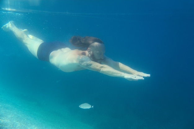 Adulto medio hombre de pelo largo barbudo nadando bajo el agua en el mar adriático mediterráneo en Croacia