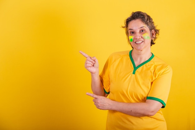 Adulto mujer adulta brasil fanático del fútbol apuntando a la izquierda publicidad foto