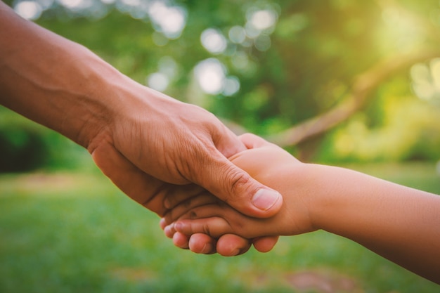 Adulto y niño estrecharme la mano aislado en un fondo verde