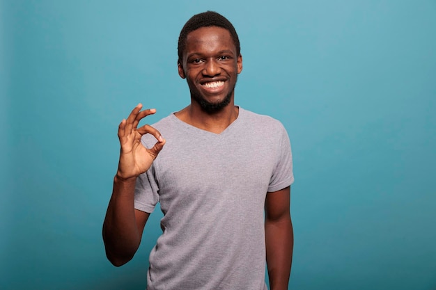 Adulto sorridente fazendo gesto bem com a mão e os dedos, aprovação de publicidade e sinal de acordo. Jovem se sentindo positivo em relação ao excelente sucesso e confiante em boas notícias.