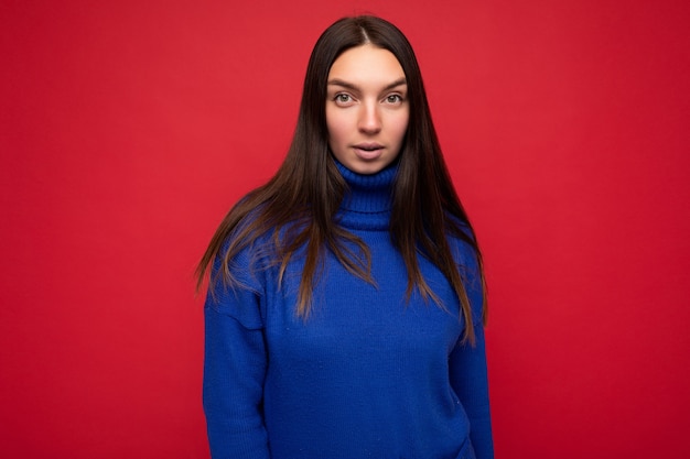 Adulto tranquilo serio bastante mujer morena con emociones sinceras aisladas en la pared de fondo con espacio de copia vistiendo un suéter azul de moda casual