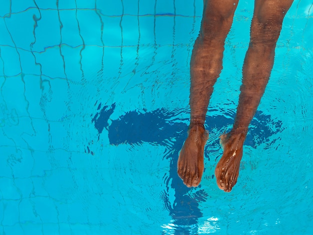 Adultos afroamericanos mans piernas bajo el agua en la piscina