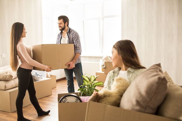 Adultos atractivos están de pie con la caja de cosas para la sala, mirándose y sonriendo