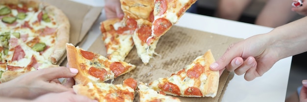 Adultos e crianças pegam fatia de pizza na caixa