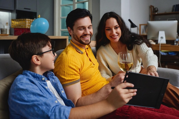 Adultos y un niño se ríen juntos mientras comparten momentos con una tableta