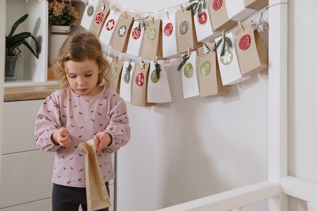 Adventskalender an der Wand hängen Kind öffnet Weihnachtsgeschenktüte