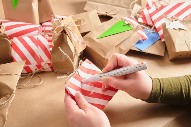 Adventskalender viele Pakete mit Überraschungen auf dem Tisch ein selbstgemachter Adventskalender Frauenhände schreiben eine Zahl