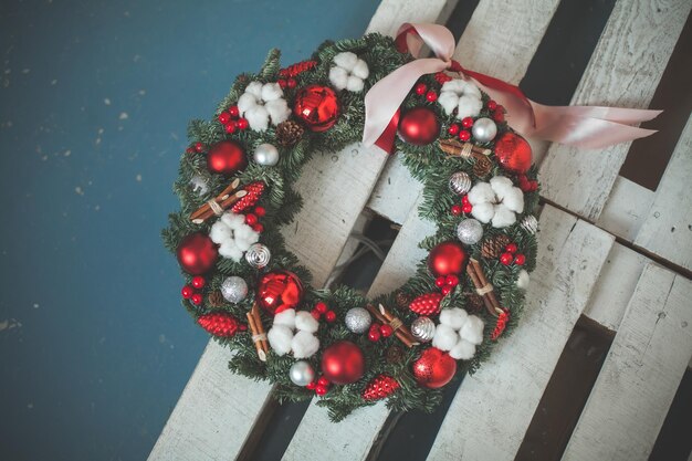 Adventskranz mit Evergreen Xmas Tree Twig, roten Glaskugeln und Beeren auf blauem Hintergrund