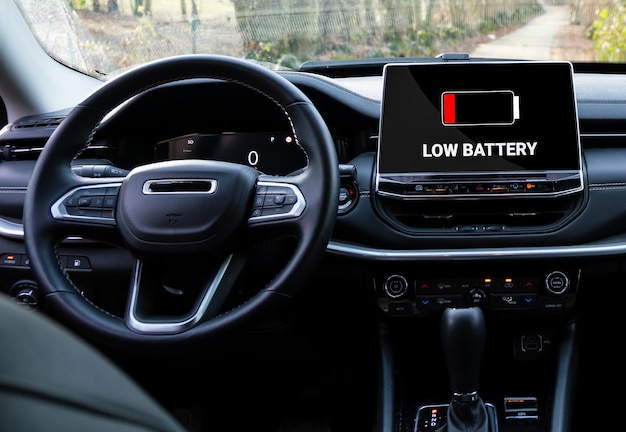 Foto advertencia de batería baja en coche eléctrico. indicador rojo en pantalla. icono de batería en el enchufe del coche híbrido.