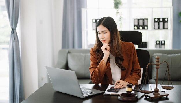 Advogada asiática conversando on-line com um cliente em um smartphone portátil discutindo detalhes de um processo no escritório