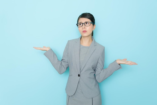 advogada muito elegante fazendo a escolha posando sentindo-se confusa e de pé no escritório de parede azul pensando em como decidir.