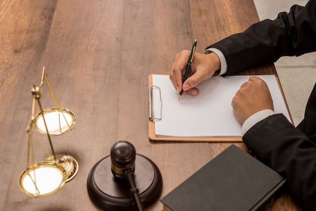 Advogado do advogado do tribunal que trabalha com originais e martelo de madeira no tabel na sala do tribunal.