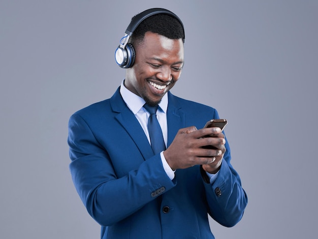 Advogado móvel e homem preto com fones de ouvido em estúdio para ouvir música streaming podcast ou rádio em fundo cinza Sorriso advogado e empregado para playlist de mídia social ou assistir vídeo