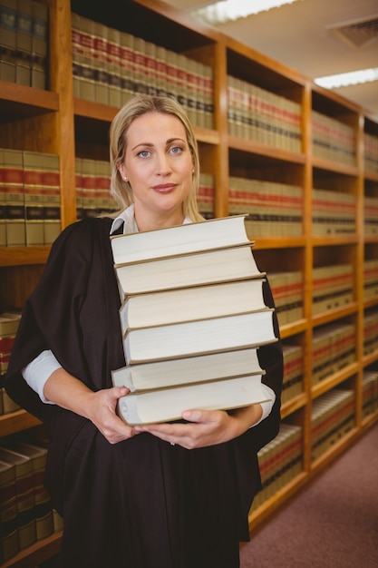 Advogado segurando uma grande quantidade de livros em pé