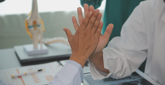 Ältere Ärzte und junge Krankenschwestern stapeln im Krankenhaus die Hände. Nahaufnahme der Hände des Ärzteteams, die Hände stapeln. Gruppe erfolgreicher Ärzte und Krankenschwestern stapelt Hände