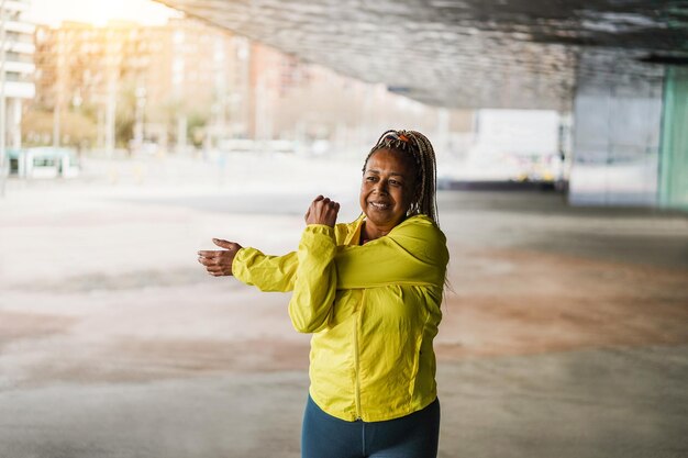 Foto Ältere afrikanische frau dehnt sich während des trainingsprogramms im freien. fokus auf gesicht