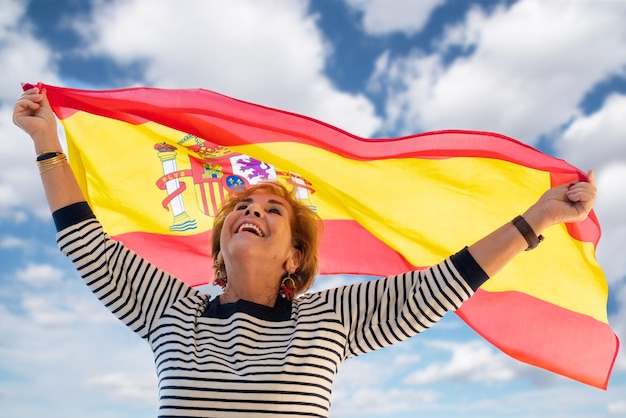 Foto Ältere dame, die stolz darauf ist, spanierin zu sein, lächelt und schwenkt die spanische flagge columbus day