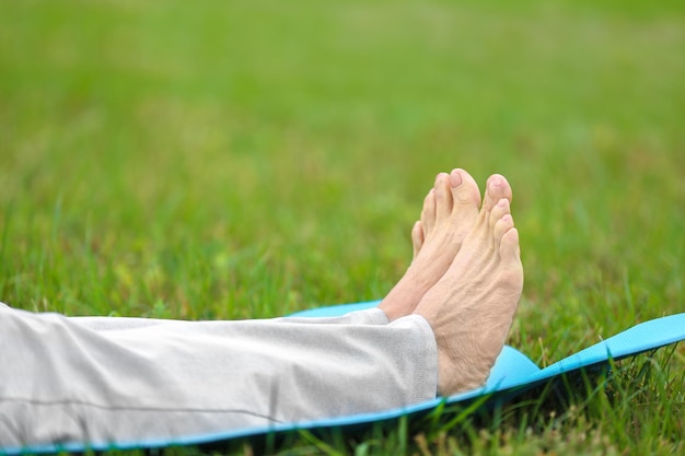 Ältere Frau auf Yogamatte im Park