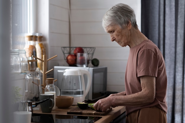 Foto Ältere frau des mittleren schusses, die avocado schneidet