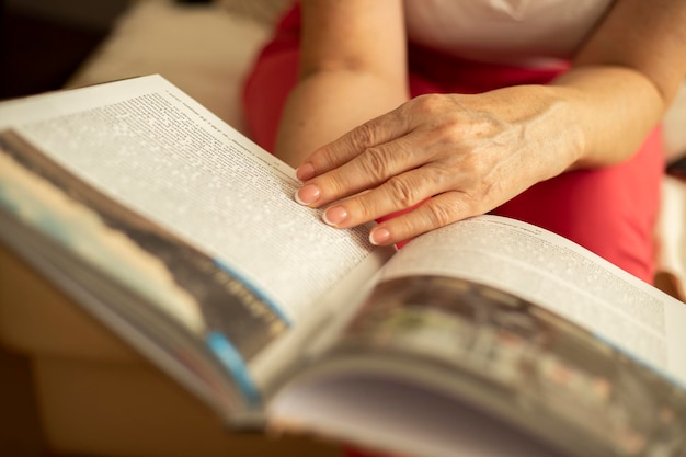 Foto Ältere frau, die ein buch durchlöchert und aus nächster nähe liest