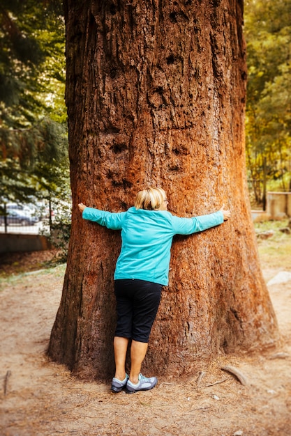 Ältere frau, die einen baum umarmt