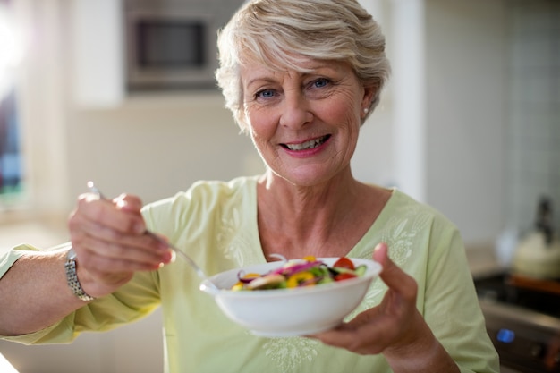 Foto Ältere frau, die gemüsesalat in schüssel hält