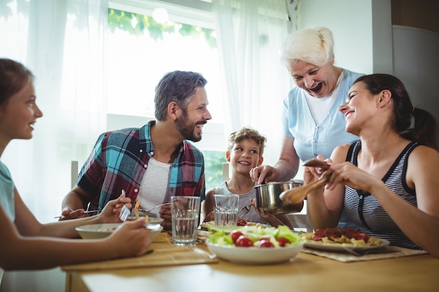 Foto Ältere frau, die ihrer familie mahlzeit serviert