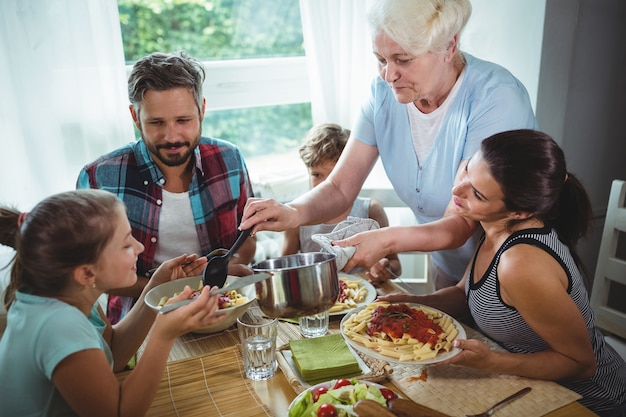 Foto Ältere frau, die ihrer familie mahlzeit serviert