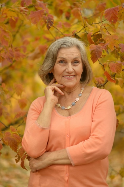 Ältere frau, die im herbst im park daumen zeigt