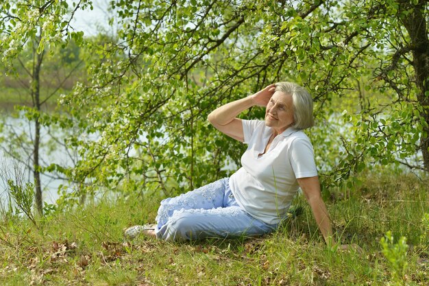 Foto Ältere frau, die im sommer nahe see sitzt