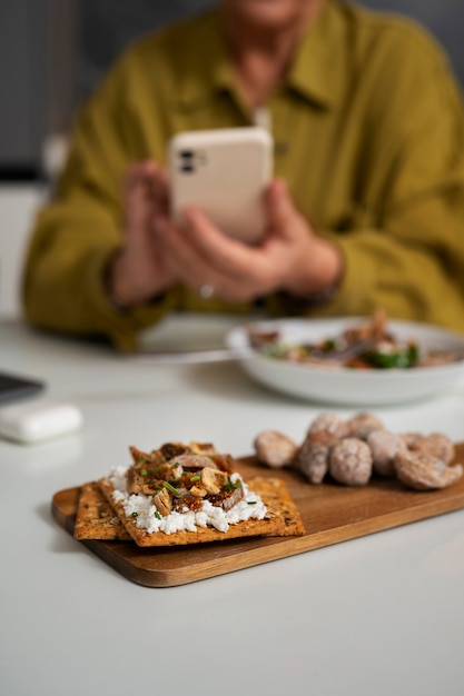 Foto Ältere frau, die zu hause feigen isst und smartphone benutzt