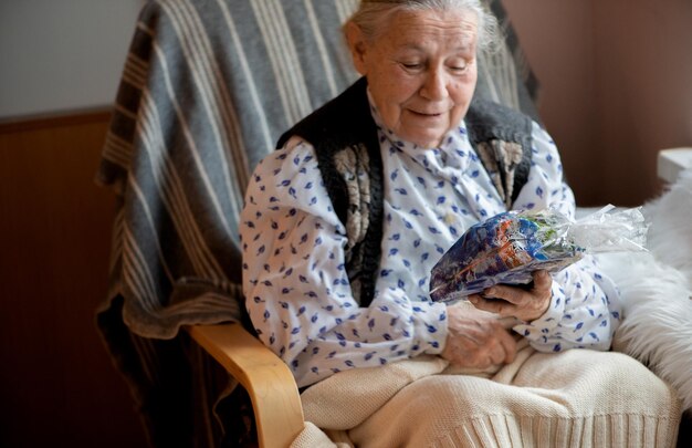 Ältere Frau freut sich über ein Päckchen Süßigkeiten, ein Weihnachtsgeschenk für ein Seniorenheim