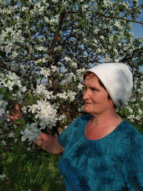 ältere Frau im Garten in der Nähe eines blühenden Apfelbaums Schönheit der Natur