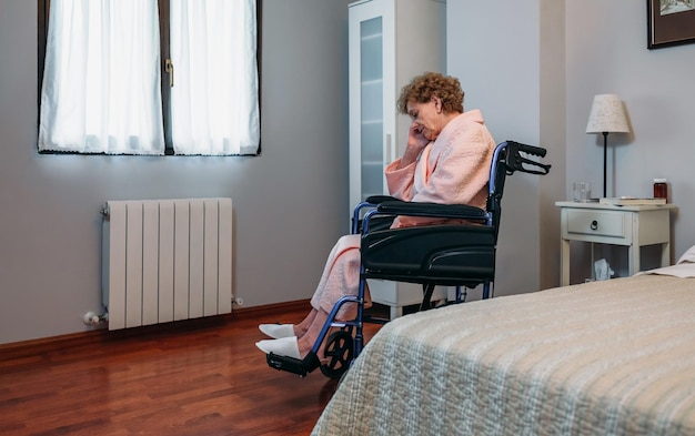 Ältere Frau im Rollstuhl allein in einem Raum