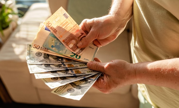Foto Ältere frau mit geld in us-dollar und euro in den händen ersparnisse aus dem rentenplanbudget