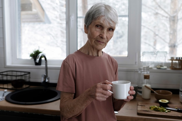 Ältere Frau mit mittlerem Schuss, die Kaffeetasse hält holding