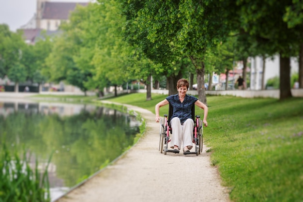 Foto Ältere frau sitzt auf einem rollstuhl am see im park