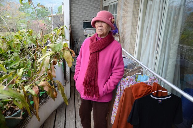 Foto Ältere frau trägt warme kleidung, während sie auf dem balkon steht