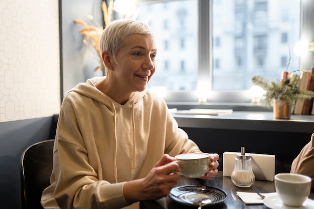 Foto Ältere frau trinkt kaffee mit freunden