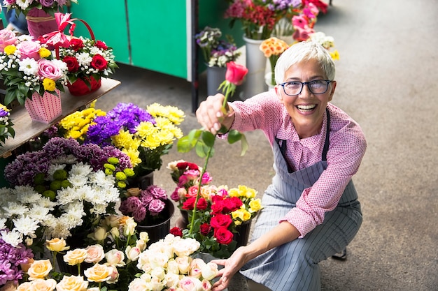 Foto Ältere frau vereinbart blumen auf lokalem blumenmarkt