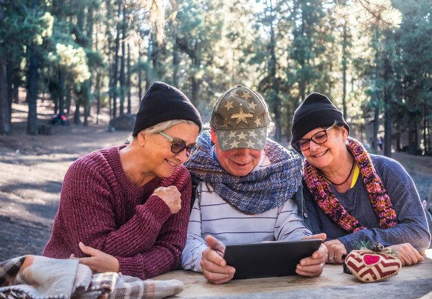 Foto Ältere freunde benutzen ein digitales tablet am tisch im wald