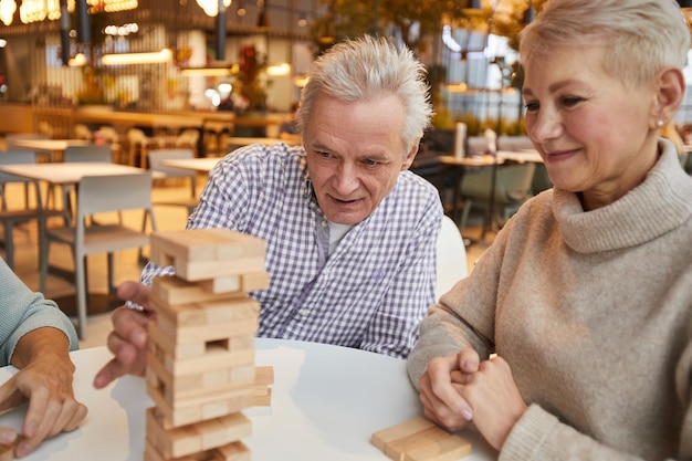 Foto Ältere freunde, die den jenga-turm blockieren