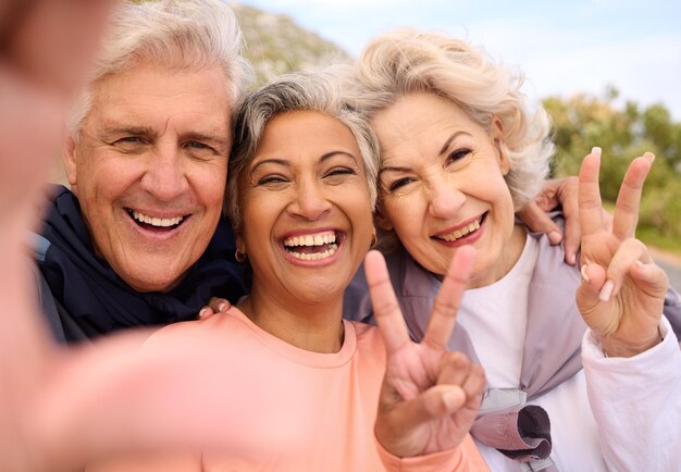 Foto Ältere freunde fitness und selfie im freien mit friedenszeichen-porträt und vielfalt in den sozialen medien fröhliche alte männerfrauen und fotografie als erinnerungs-emoji oder profilbild für das training im ruhestand