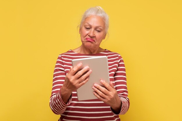 Ältere hispanische Frau liest Nachrichten auf dem Bildschirm des Tablets